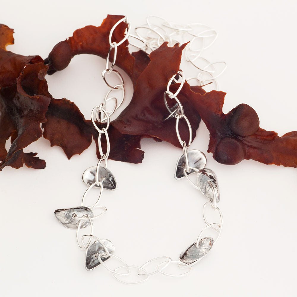BLÅMUSSLA NÄT airy long silver chain necklace with shell accents draped around the neck