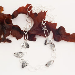 BLÅMUSSLA NÄT airy long silver chain necklace with shell accents draped around the neck