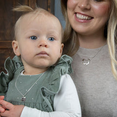 Mamma och bebis bär matchande silver MAMA halsband med klöverformade hänge