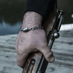 BLÅMUSSLA ROBUST armband worn on the wrist with a shell pendant on a silver link chain