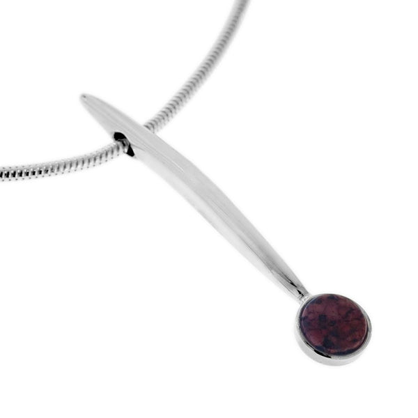 Närbild av PEAK GRANIT halsband med silver stav och röd granitsten mot vit bakgrund
