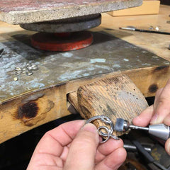 Craftsman shapes a silver Råbandsknop Hjärta pendant on a workbench