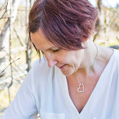 Kvinna bär ett silverhalsband med ett hjärtformat hängsmycke av små hjärtan