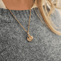 Person bär ett 18K guld Ros halsband med diamant mot en grå stickad tröja.