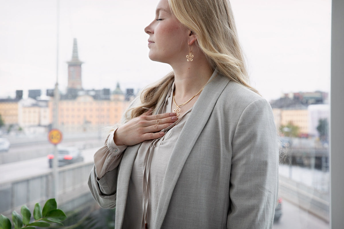 Modell med Blomman-smycken vid ett fönster med utsikt över Stockholm.