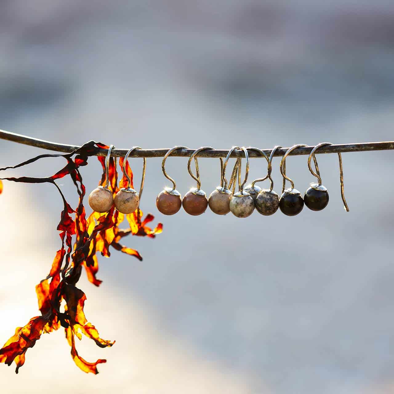STRAND örhängen i nickelfri sterling silver med polerade strandstenar hängande från en gren