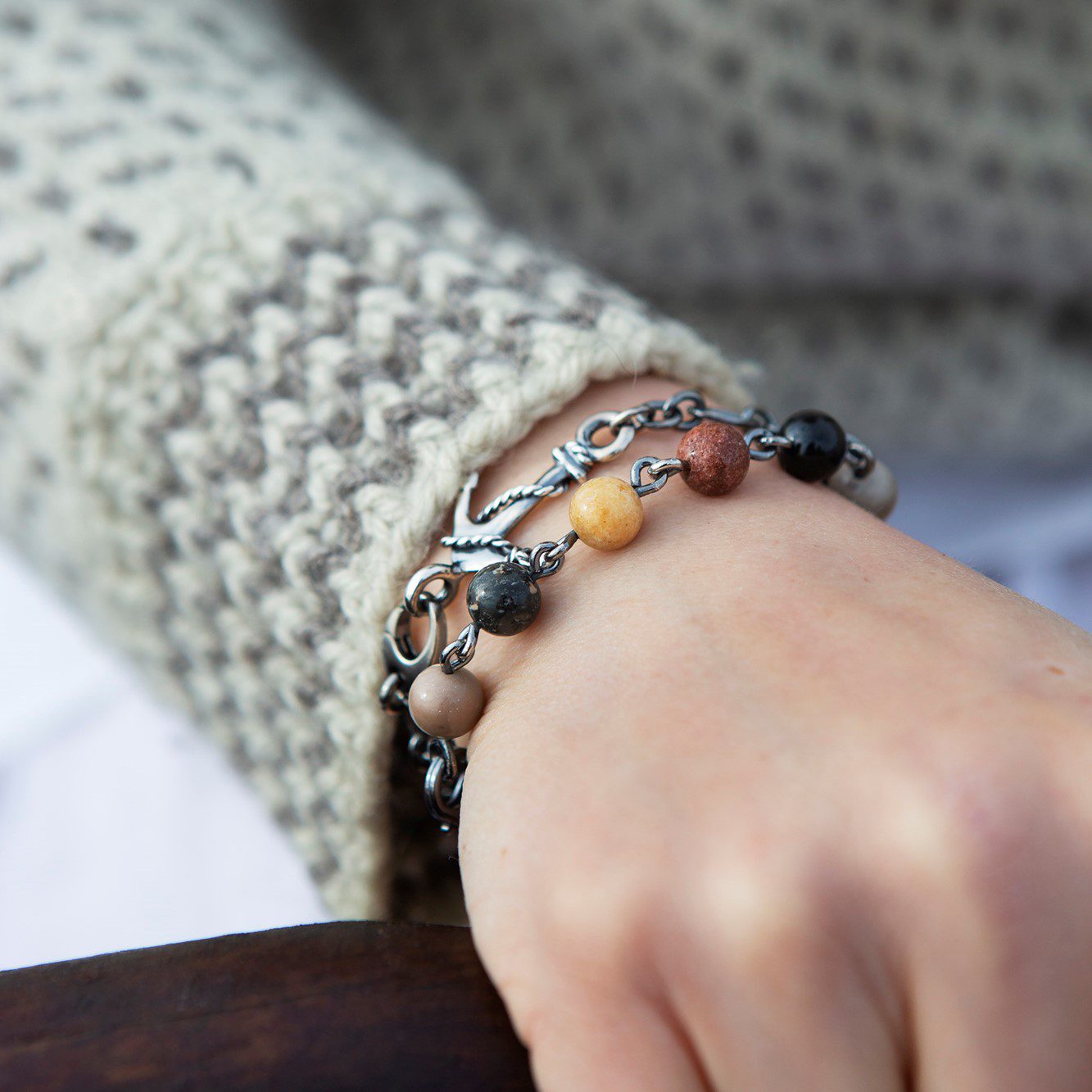 Wrist wearing stacked STRAND armband beads in earthy tones with a silver chain.
