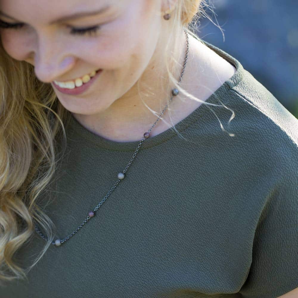 STRAND halsband 60 cm i silverkedja med färgade stenar på en kvinna i grön topp